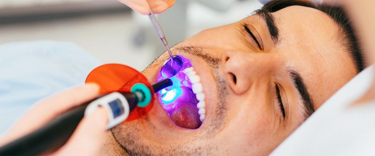 Female dentist using a dental curing light.